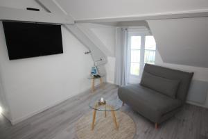 sala de estar con silla y TV de pantalla plana en DU SEL A LA VIE, grand studio entre marais et océan, en Batz-sur-Mer
