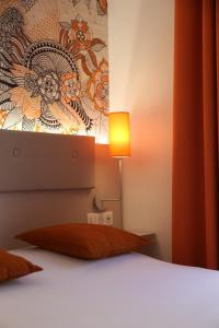 a bedroom with a bed with a lamp next to it at Hotel Victoria in Strasbourg