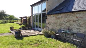 een stenen huis met een tafel en stoelen in een tuin bij The Byre North End Farm in Ashton Keynes