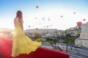 a woman in a yellow dress looking at hot air balloons at Carus Cappadocia in Göreme