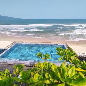 a swimming pool next to a beach with the ocean at M SUITE Danang Beach in Da Nang