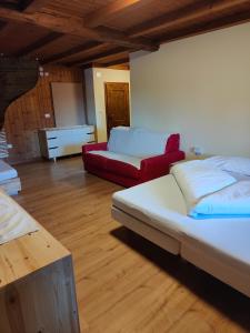 a living room with two beds and a red couch at Maso Kofler in Rumo