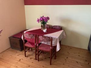 uma mesa com cadeiras cor-de-rosa e um vaso de flores roxas em Vineyard Cottage Slanc em Metlika