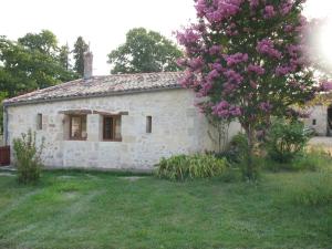 Gite Le Chardon Fleuri في Teuillac: منزل حجري صغير مع شجرة ورد أرجواني