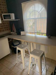 a kitchen with a counter with two stools and a microwave at 20 On Plover - Private Cottage in Sandton