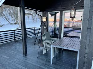 un porche con banco, mesa y sillas en Aurora woods en Skjervøy