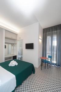 サン・ベネデット・デル・トロントにあるSeven Roomsのベッド、テーブル、椅子が備わるホテルルームです。
