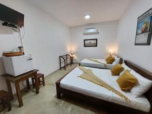 a bedroom with two beds and a television in it at Kingcity Resort in Anuradhapura