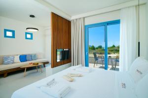a white bedroom with a bed and a living room at Narciso Thassos Luxury Suites in Skala Prinou