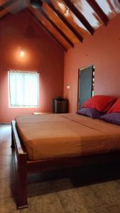 a bedroom with a large bed with orange walls at My Village in Tissamaharama