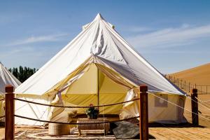 ein großes weißes und gelbes Zelt in der Wüste in der Unterkunft Ming Sha Mountain Wild Hostel in Dunhuang