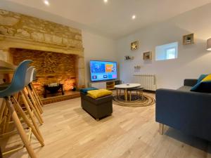 ein Wohnzimmer mit einem Kamin und einem TV in der Unterkunft Montignac-Lascaux - Les Pierres d'Alexandre in Montignac