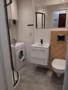 a bathroom with a sink and a washing machine at KAWALERKA 28M SALON Z KUCHNIĄ CENTRUM NOWY SĄCZ in Nowy Sącz