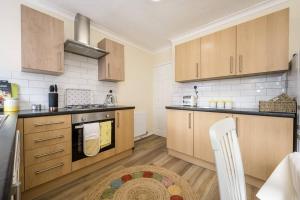 a large kitchen with wooden cabinets and a rug at Cherry Tree Cottage in Thornton