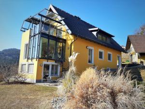a yellow house with large windows on top of it at Auszeit am Weinhof in Loschenthal +19 photos