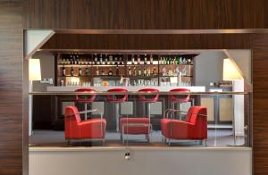 a bar with red chairs and a counter with alcohol at Hôtel Le Méditerranée in Lourdes