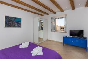 um quarto com uma cama roxa e uma televisão em Apartment Toma em Dubrovnik