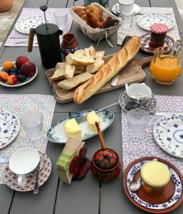 einen Tisch mit Teller mit Speisen, Brot und Käse in der Unterkunft Hôtes de Maïa Chambre d'hôtes in Moret-sur-Loing