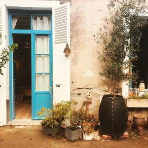 Ein Haus mit einer blauen Tür und einem Haufen Topfpflanzen in der Unterkunft Hôtes de Maïa Chambre d'hôtes in Moret-sur-Loing