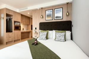 a bedroom with a large white bed with a green rug at Wilde Aparthotels Manchester St. Peters Square in Manchester
