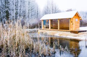 une cabane dans la neige à côté d'un étang dans l'établissement Hotel Głęboczek Vine Resort& Spa, à Wielki Głęboczek