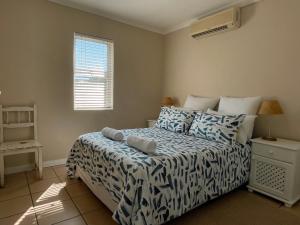 Un dormitorio con una cama con sábanas azules y blancas y una ventana en Waterfront 2 Bedroom Apartment, en Richards Bay