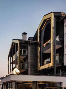 an external view of a black building with balconies at Alpin Garden Luxury Maison & SPA - Adults Only in Ortisei