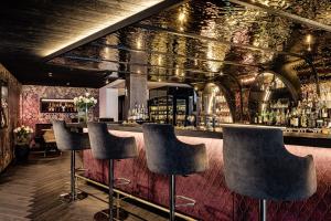 a bar with black stools in a room with floral wallpaper at Alpin Garden Luxury Maison & SPA - Adults Retreat in Ortisei