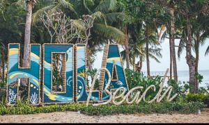 un cartello sulla spiaggia con palme sullo sfondo di Hola Beach - Beach Club & Eco Glamping Resort a Ke Ga