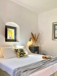 a bedroom with a bed with white sheets and a window at Cortijo El Pozuelo in Tarifa