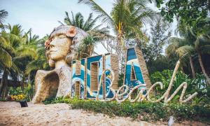 Un cartello sulla sabbia davanti a una statua. di Hola Beach - Beach Club & Eco Glamping Resort a Ke Ga