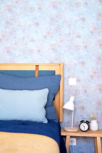 a bed with a blue pillow and a table with a clock at Blue by the River 2 - elegant two-bedroom in Santos in Lisbon
