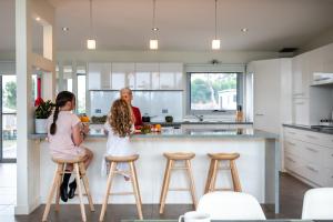 Burraneer - Freycinet Holiday Houses في كولز باي: بنتان يجلسن على مقاعد الحانة في مطبخ
