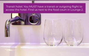 two empty glasses sitting on a sink next to a faucet at YOTELAIR Amsterdam Schiphol Transit Hotel in Schiphol