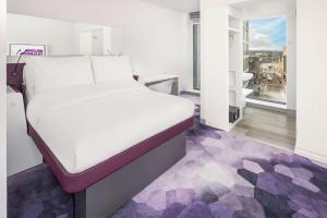 a room with a bed, a dresser, and a window at YOTEL Glasgow in Glasgow
