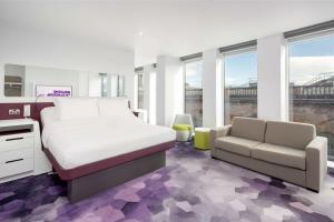 a bedroom with a bed and a couch and windows at YOTEL Glasgow in Glasgow