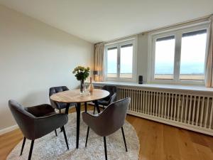 a dining room with a table and chairs and windows at Norderhof Kliffsand 15 in Kampen