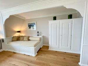 a white bedroom with a bed and a cupboard at Norderhof Kliffsand 15 in Kampen