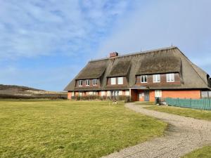 um velho celeiro com um telhado de palha e um campo de relva em Norderhof Kliffsand 19 em Kampen