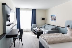 ein Hotelzimmer mit einem Bett und einer Couch in der Unterkunft TIDE Hotel in Wilhelmshaven