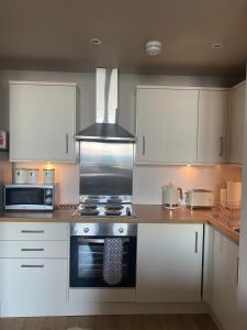 uma cozinha com armários brancos e um forno com placa de fogão em Breakwater em North Berwick