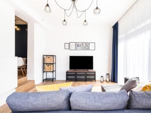 a living room with a blue couch and a tv at Kompleks Wypoczynkowy Pomerania in Rewal