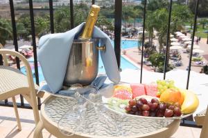 un tavolo con un cesto di frutta e una bottiglia di vino di Tsokkos Gardens Hotel a Protaras