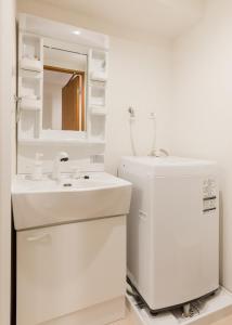 a white bathroom with a sink and a mirror at Dash Living Shinjuku in Tokyo