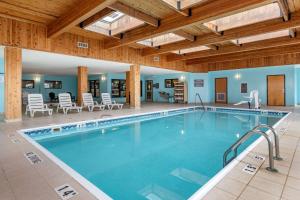 einen Pool in einem Hotel mit Stühlen und einem Tisch in der Unterkunft Comfort Inn & Suites in Grand Blanc