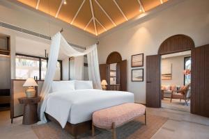 um quarto com uma grande cama branca e uma cadeira em Radisson Resort Phan Thiet em Phan Thiet