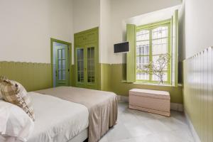 um quarto com paredes verdes, uma cama e uma janela em La Abadia de Giralda em Sevilha