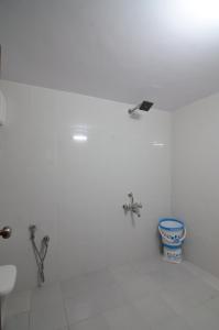 a white bathroom with two faucets and a toilet at Bhumi Cottage in Revadanda