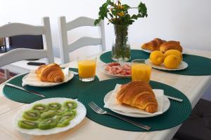 uma mesa com pratos de alimentos para o pequeno-almoço e sumo de laranja em apart@CostaSantoAndré Beach em Santiago do Cacém