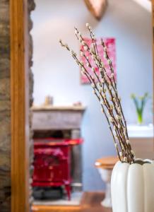 a white vase with flowers in it next to a fireplace at Sunnyside Bed and Breakfast in Longnor